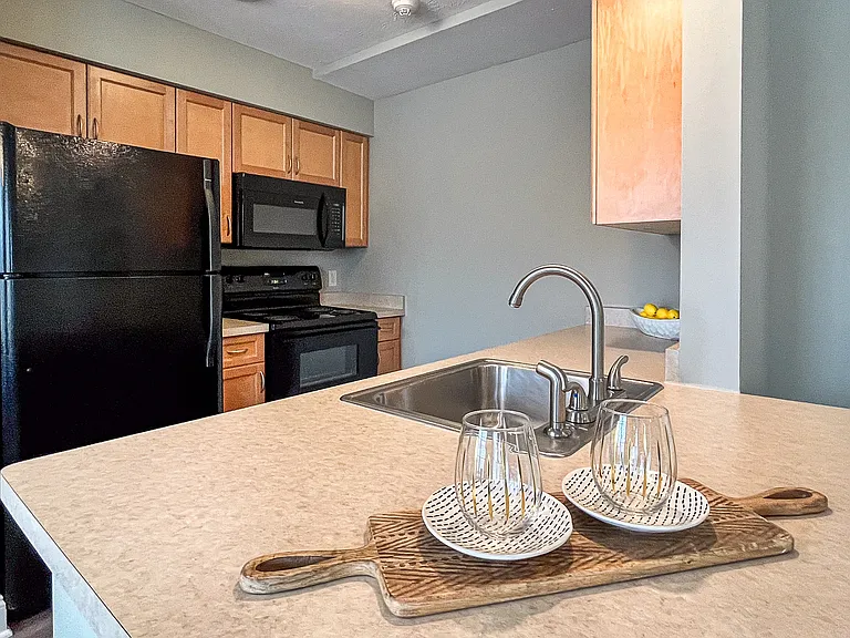 View from breakfast bar of well equipped kitchen with wood cabinetry and black appliances