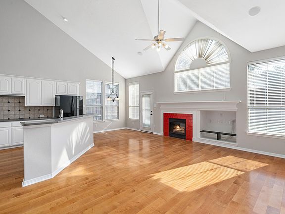 Living room and kitchen with plenty of natural light, decorative backsplash, kitchen island and soaring ceiling