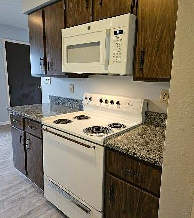 Granite countertops, electric stove and over the stove microwave.
