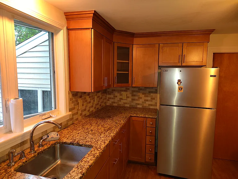 Kitchen showing wooden cabinets and stainless steel refrigerator. Pocket door to the dining/living room to the right of the refrigerator.