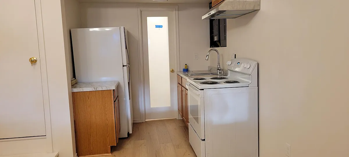 Kitchen area leading to bathroom door. Full size Refrigerator, electric stove, and kitchen sink. Microwave, toaster, blender, pretty much all the goodies a real kitchen needs. - 1819 Cliff St #B