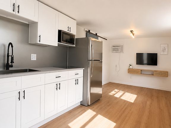 Bright open living area with kitchen, wood flooring, and moder finishes.