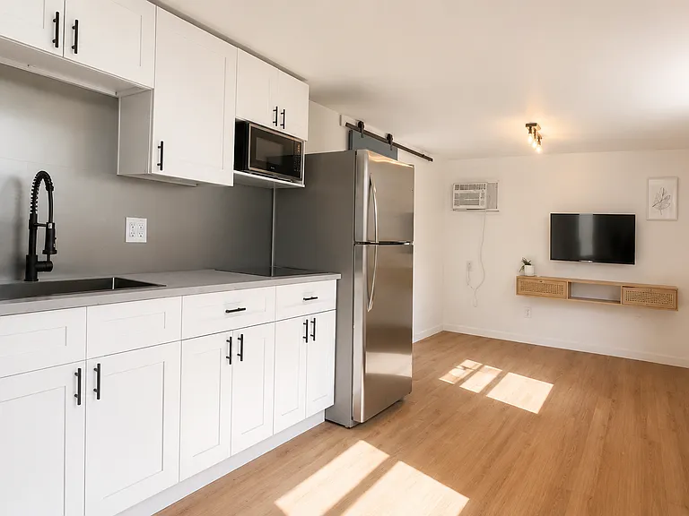 Bright open living area with kitchen, wood flooring, and moder finishes.