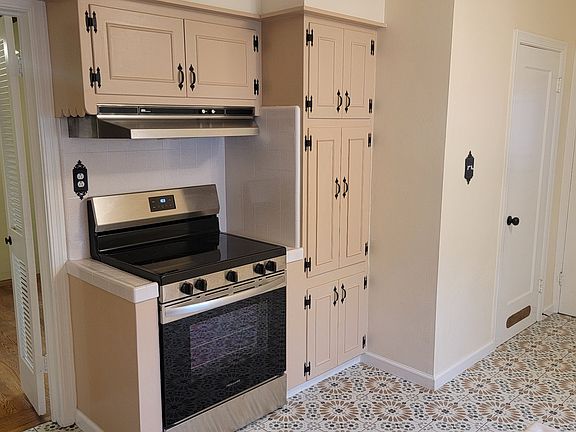 Kitchen with oven, stove, hood, microwave behind cabinets, back door