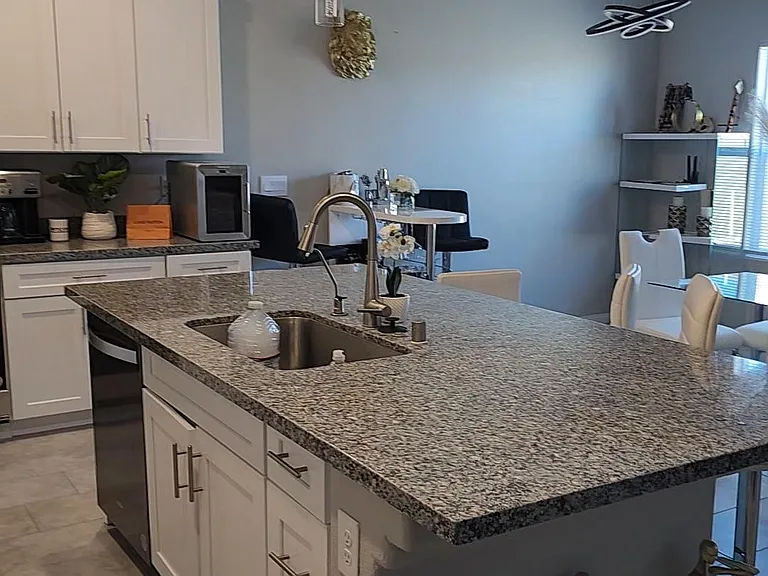 Open kitchen with a large granite island, undermount sink, ample cabinetry, and nearby dining space for easy meals.