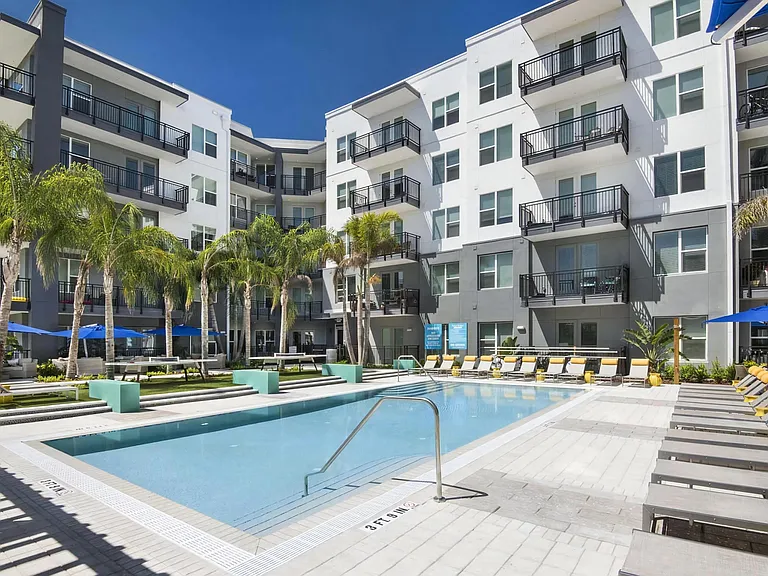 Resort-Style Pool Surrounded by Palm Trees, Sun Loungers, and Courtyard Views