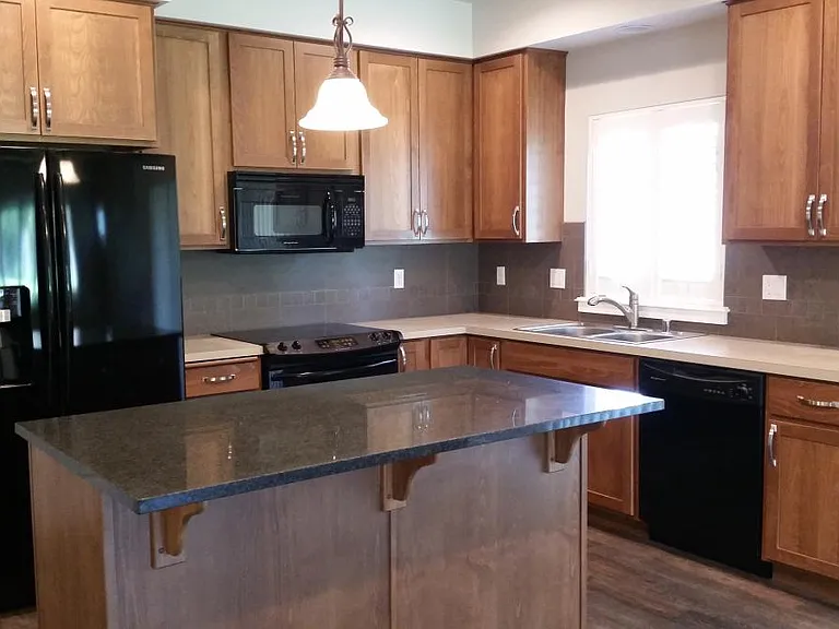Kitchen with Large Granite Island and window for natural light. Refrigerator and stove has been upgraded to stainless steel