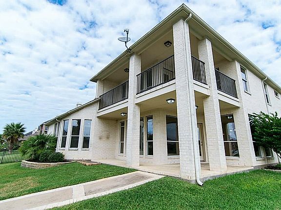Rear of this beautiful home of the balcony and patio that overlooks two lakes
