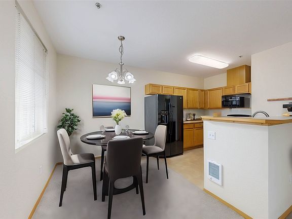 Cozy dining area adjacent to a modern kitchen. Photo is virtually staged.>