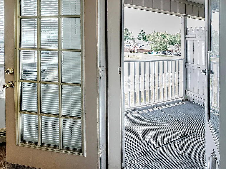 Inviting balcony view with elegant glass door, perfect for relaxing and enjoying the neighborhood scenery.