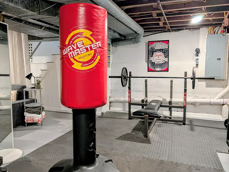 The basement also includes a weight bench, workout space, and shelves for storage