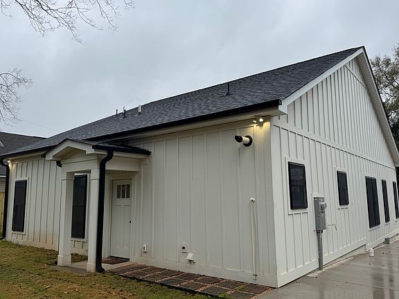 Board and batten outside with black roof , windows with screens and gutters.