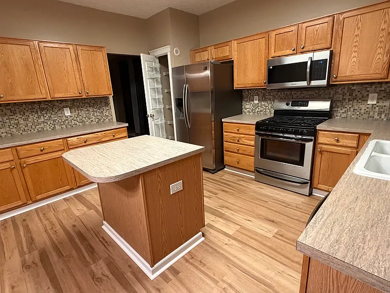 Beautiful kitchen with farmhouse double bowl sink and glass tiles all around above the counters.