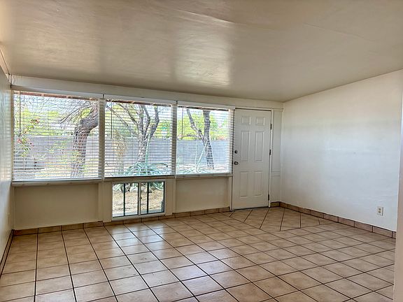 Living area with large windows with blinds. Ceramic tile.