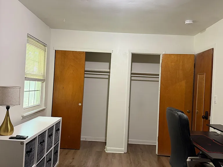 Private bedroom with a window and two closets, offering ample hanging and shelf space for organized storage.