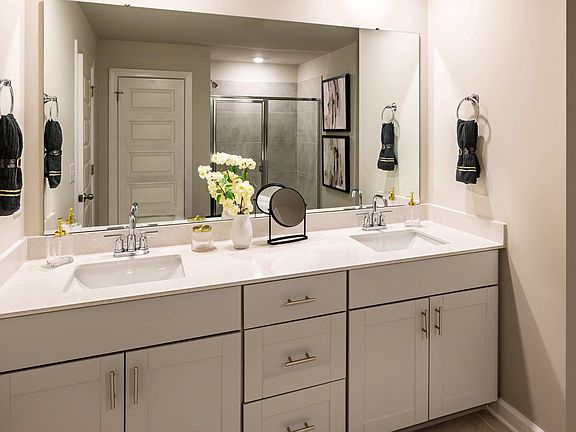 The primary bath offers dual vanity sinks and a walk-in shower. Photography from Holland Park.