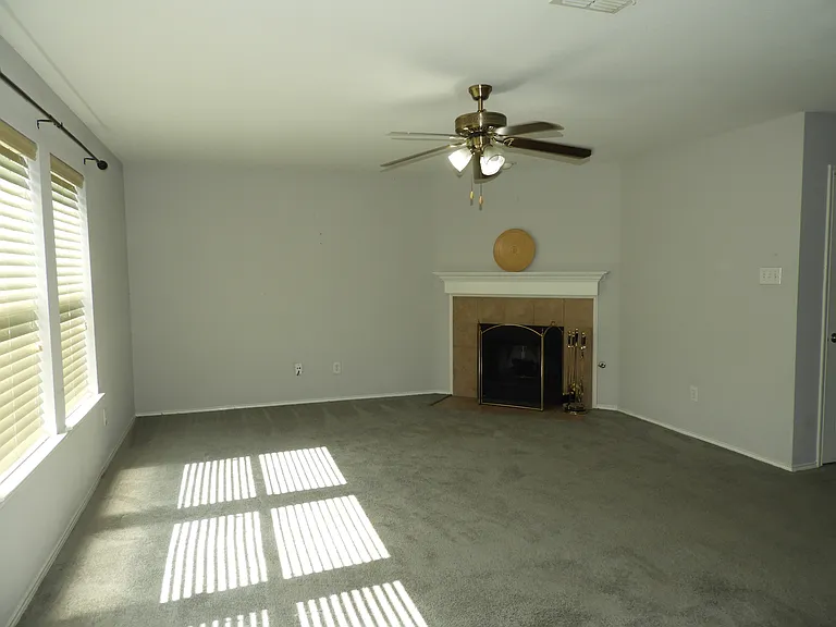 Living Room with large windows, corner fireplace and ceiling fan.