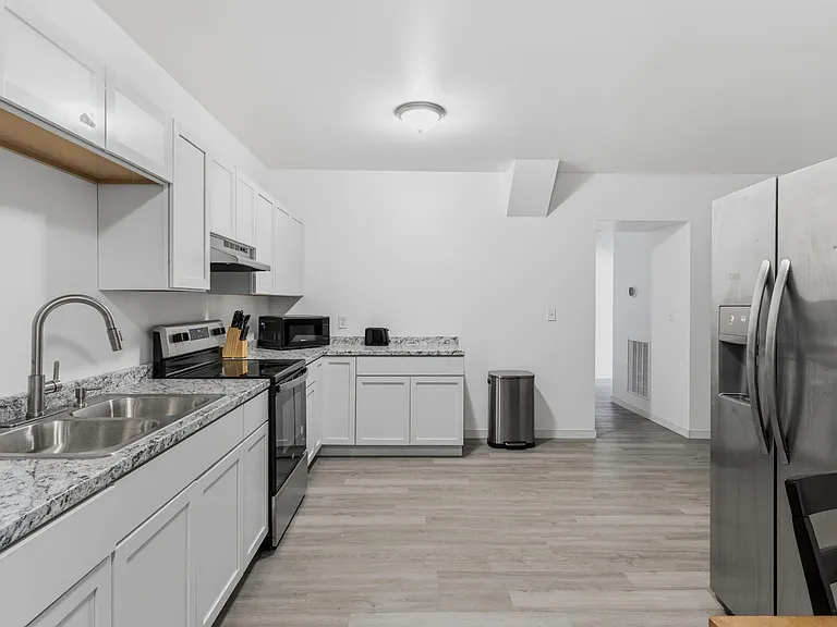 Efficient galley kitchen with ample white cabinetry, granite-look counters, and stainless appliances for everyday cooking.