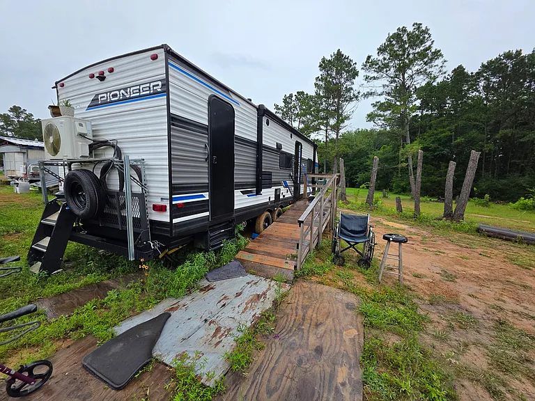 Private entry with elevated deck and ramp, offering outdoor seating and views of the surrounding wooded lot.