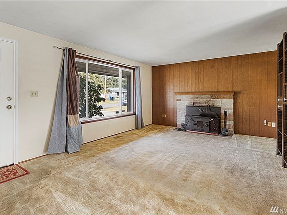 Good sized living room with wood burning insert and shelving unit that stays. Beautiful hardwoods under carpet! 