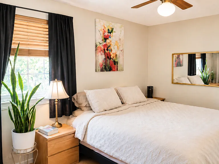 Main bedroom with south facing window, hardwood floor, 2 closets, and ceiling fan.