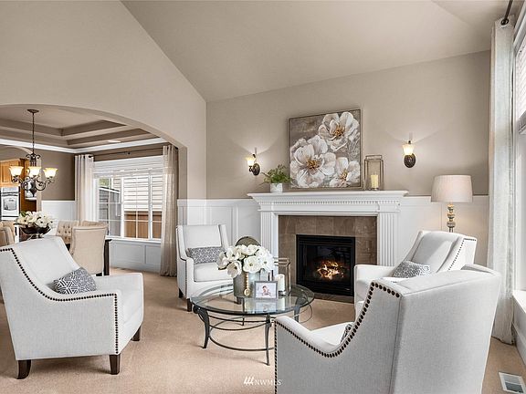Formal living room with wood-wrapped gas fireplace and an abundance of windows allowing natural light to pour in.