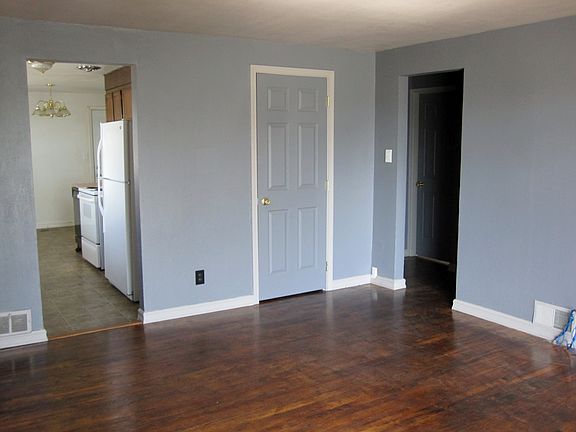 Living room has wood flooring & a view into kitchen & hallway