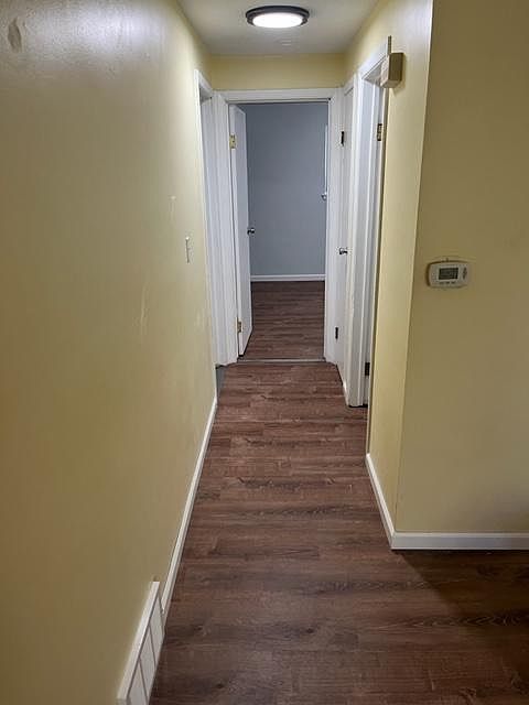 Hallway with new flooring, paint, baseboards, vents, lights, and outlets.