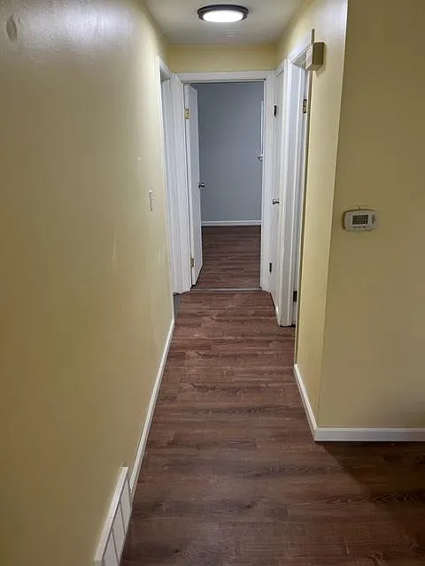 Hallway with new flooring, paint, baseboards, vents, lights, and outlets.