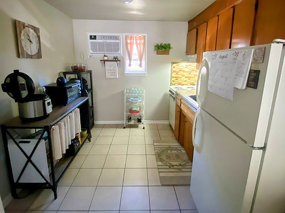Kitchen equipped with apartment size stove, refrigerator, wall air conditioning unit and plenty of cabinet space for storage.