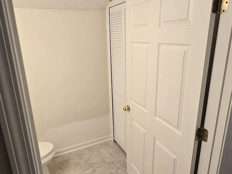 View into the half bath from the hallway looking at laundry doors