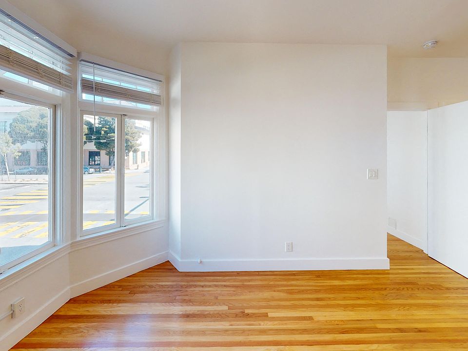 Sunlit living room with a large window and wood-like flooring