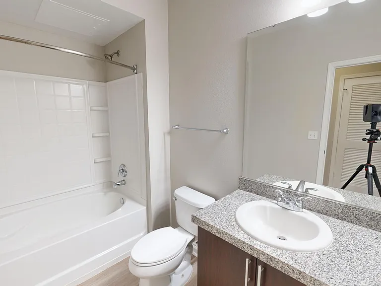 Apartment bathroom with large soaking tub and wood-style flooring.