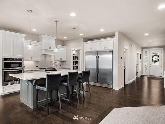 The gorgeous gourmet kitchen sparkles with sleek stainless appliances, fully tiled backsplash, slab counters, oversized breakfast bar island. 