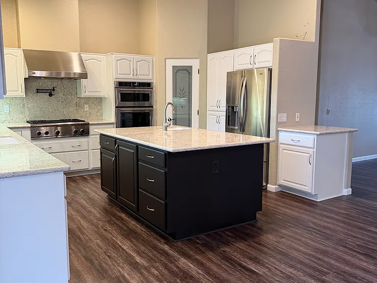 Large kitchen with lots of storage, island, pantry, and under cabinet lighting flows seamlessly into open concept living space