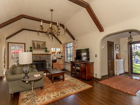 As you enter the oversized living room, you are immediately aware of the grand cathedral height ceilings with classic Tudor wood beams. You will enjoy many good times in this room with the wood burning stone fireplace, wrought iron windows and french door