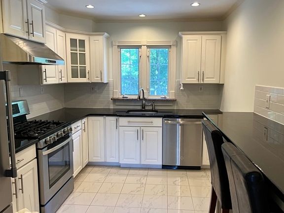 Kitchen with stainless steel appliances and a green view.
