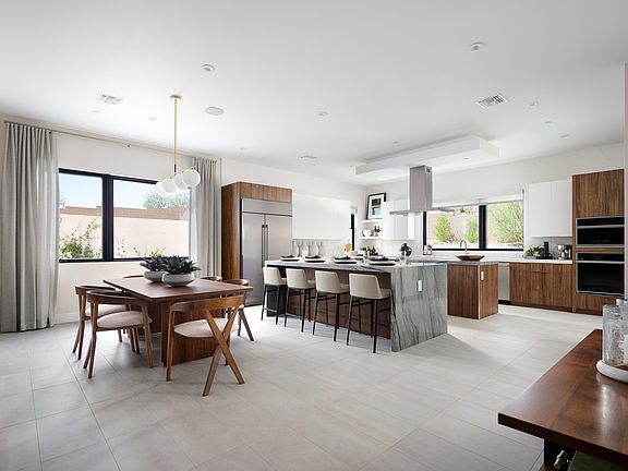 A modern, open-concept kitchen and dining area with sleek, wooden cabinetry, a large island, and a d