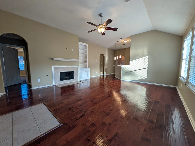 This perspective features the charming gas fireplace and a large, integrated white built-in shelving unit, adding character and storage to the room's extensive square footage.