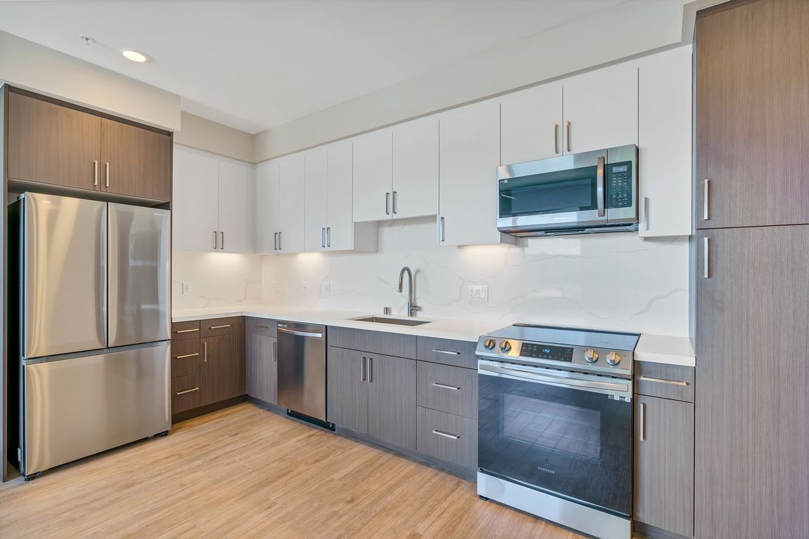 This full kitchen has a large sink, French-door fridge, dishwasher, microwave, stovetop oven, and a full pantry.