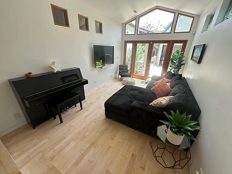 Open plan high ceiling living area with piano, 60" screen, Sonos, etc - french doors to backyard