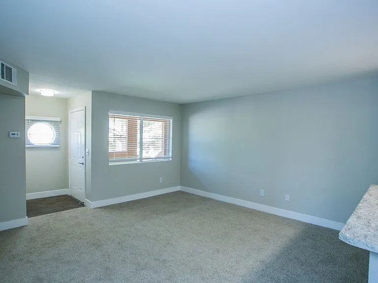 Carpeted living area with large baseboards, two-tone paint, and windows.