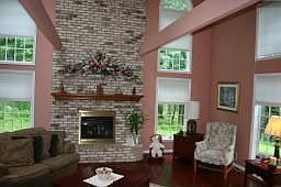 Stone fireplace with high ceilings and exposed beam and balcony 