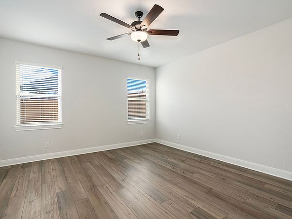 Spacious master bedroom with two windows and a ceiling fan.