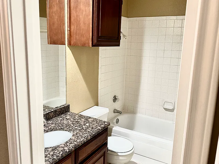 Guest bathroom with shower/tub combo, granite countertop.