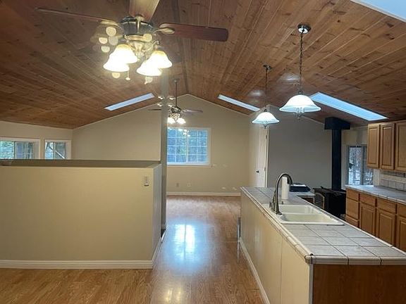Looking into 2nd floor. Kitchen on near right. Bath on far right past wood stove. Dining area on near left then staircase and then living area on other side of staircase