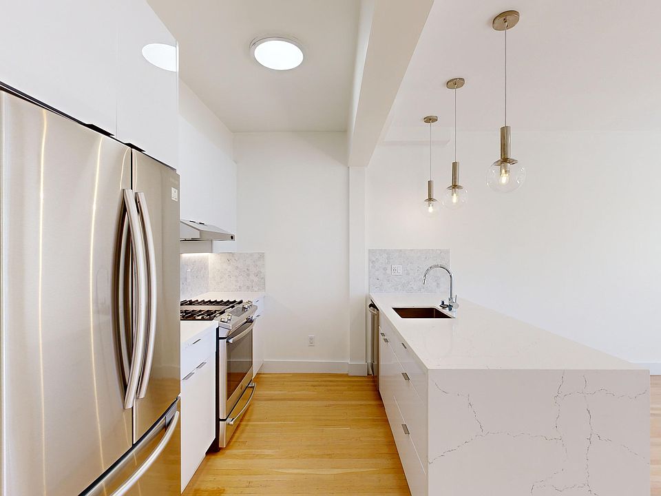 Kitchen with multiple cabinets, refrigerator, stove, range hood, and sink