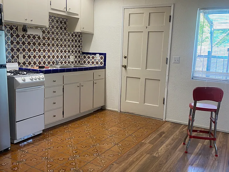 Kitchen includes artistic tile backsplash, refrigerator, stove/oven and microwave.