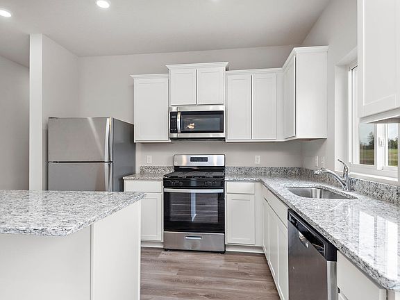 The kitchen has stainless steel appliances and plank flooring.