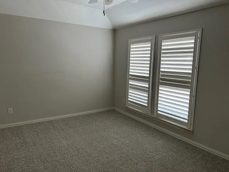 Secondary bedroom with plantation shutters, ceiling fan and walk-in closet.